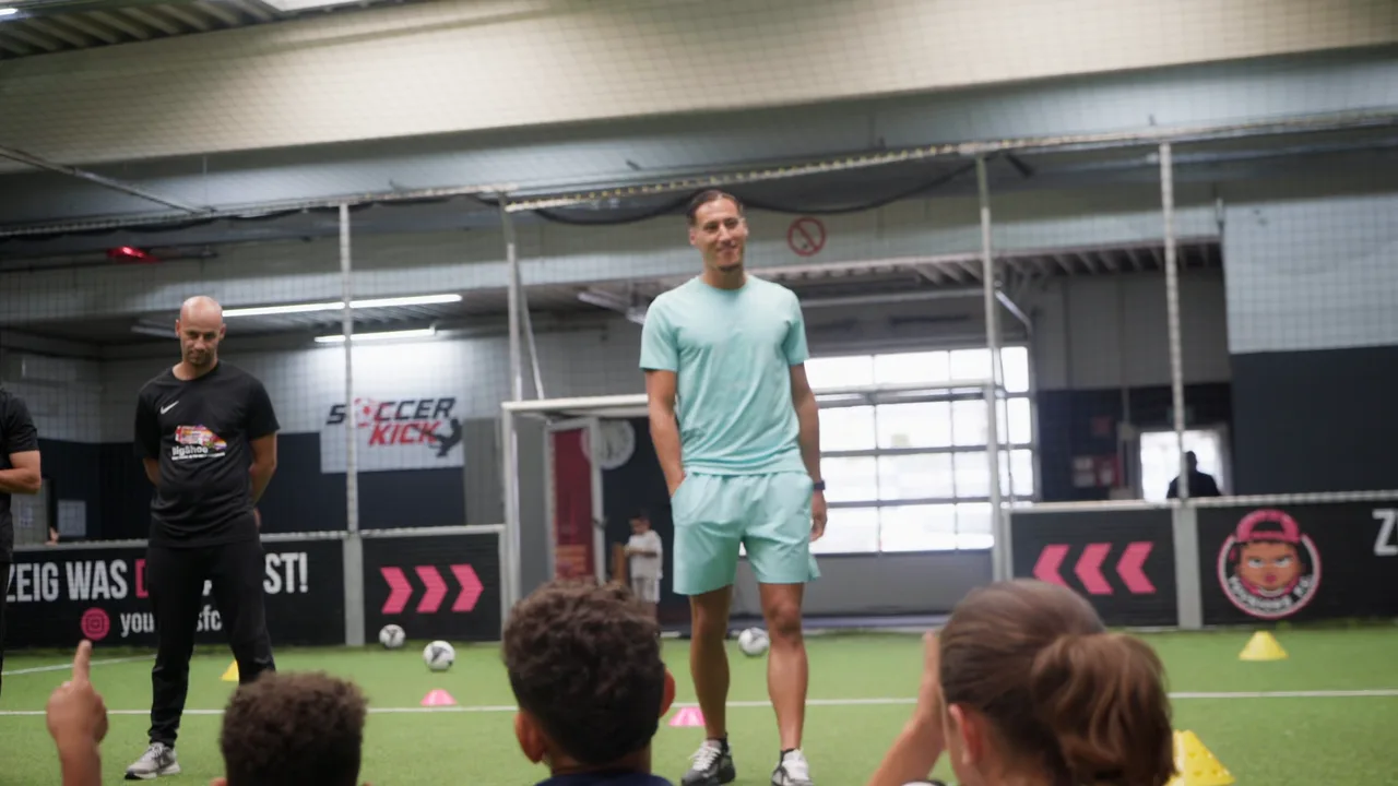 Ein Fußballer in hellgrünem Trikot steht lachend auf einem Hallenplatz