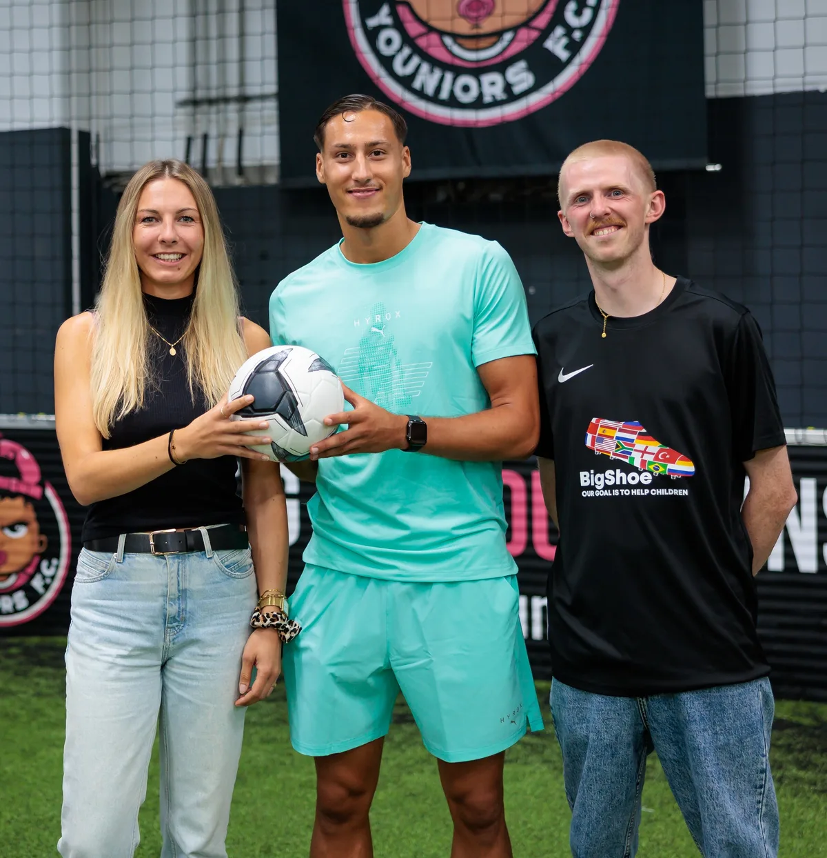 Younes Ebnoutalib mit einem Ball zwischen einer Frau und einem Mann im BigShoe-Shirt